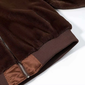 Detailed close-up of dark brown plush jacket showing ribbed hem and metallic zipper