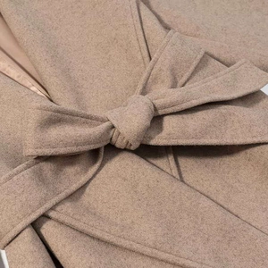 Detailed macro view of camel wool coat fabric texture with matching waist belt tie