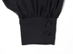 Detailed view of sheer chiffon lantern sleeves with elegant buttoned cuffs on black top