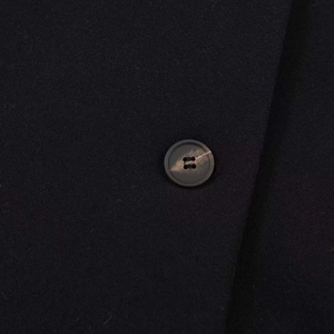 Detailed close-up of thick black wool fabric and brown marbled button on jacket