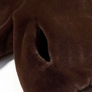 Detail of dark brown faux fur jacket showing plush texture, side pocket and ribbed hem