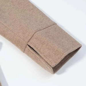 Close-up of split cuff detail on long wool blend coat in elegant camel brown color