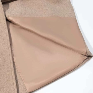 Macro shot of camel wool coat detail showing textured fabric and smooth satin lining