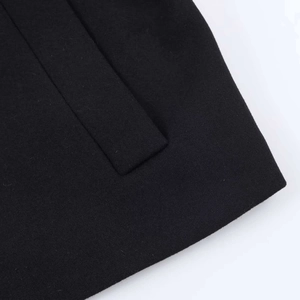 Detail of the rectangular pocket flap on a black wool-blend short jacket with neat stitching