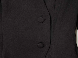 Close-up detail of black slim-fit blazer showing twill fabric texture and fabric-covered buttons