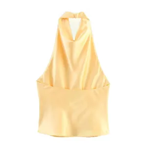 Detail view of yellow halter neck top showing smooth satin texture and elegant draping