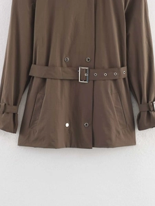 Close-up of brown trench coat featuring double-breasted buttons and adjustable belted waist