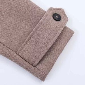 Detail of tan wool coat sleeve featuring a woven texture and decorative buttoned strap