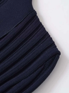 Nahaufnahme von dunkelblauem Strickstoff mit feiner vertikaler Rippenstruktur und Verarbeitung