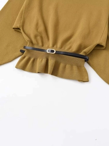 Detailed view of ginger yellow knit top with ruffled hem and black belted waist