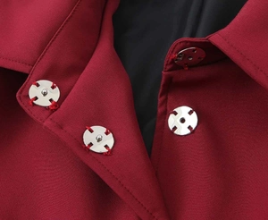 Dettaglio di bottoni in metallo argento su un blazer bordeaux con fodera nera