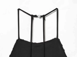 Detail of the back neck closure with white button on a black halter neck dress