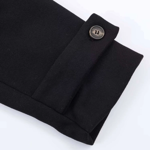 Close-up detail of a black wool jacket sleeve featuring a textured button and cuff strap