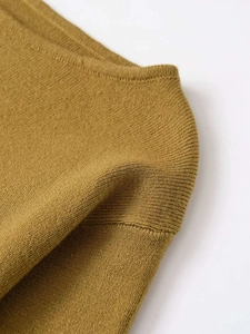 Close-up of mustard yellow knit sweater showing fine stitching and premium fabric texture