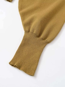 Close-up of ribbed cuffs on mustard yellow knit sweater showing detailed knitting texture