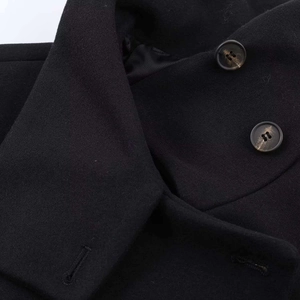 Close-up of black wool jacket collar with textured buttons and striped satin lining
