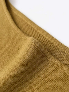 Close-up of mustard yellow knit fabric showing ribbed texture and fine craftsmanship