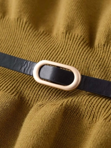 Detail of olive green knit fabric with a black leather belt and gold oval buckle