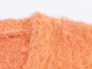 Vue macro détaillée montrant la texture pelucheuse orange et les fibres de fausse fourrure