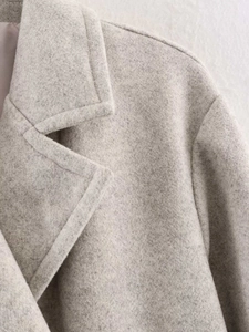 Detail of light gray wool blend coat showing high-quality lapel stitching and fabric texture
