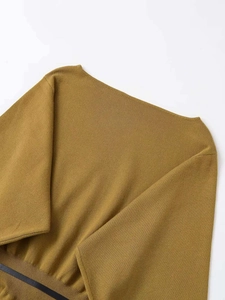 Close-up of ginger yellow knit top featuring a ribbed hem and black belt decoration