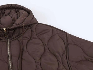 Détail de la veste matelassée marron foncé avec coutures oignon et fermeture dorée