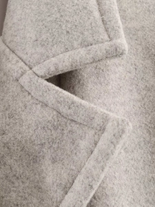 Detail shot of light grey wool blend coat showing lapel collar and topstitching texture
