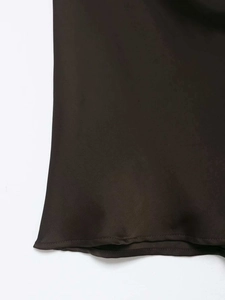 Gros plan sur l'ourlet en satin et les coutures fines du haut dos nu sombre