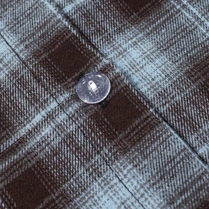 Close-up of brown and blue plaid fabric texture with a transparent resin button detail