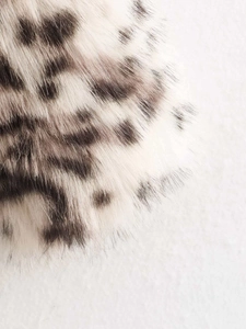 Gros plan détaillé de la texture en fausse fourrure léopard avec de douces taches noires et blanches