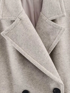 Detailed close-up of wool fabric texture with lapel collar and black buttons on gray coat