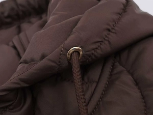 Gros plan du tissu matelassé marron avec œillet en métal doré et cordon de serrage