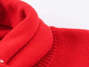 Macro close-up showing the fine knitted texture and ribbed cuff of the red cardigan