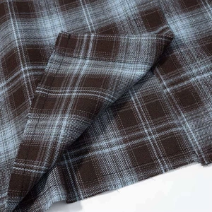 Close-up of brown and blue plaid fabric detail with precision stitching on shirt hem