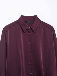 Close-up of wine red satin shirt featuring smooth texture and matching buttons