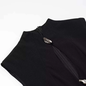 Detail of high collar black dress featuring textured fabric and gem-like button accents
