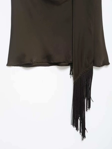 Gros plan sur le tissu en satin olive soyeux avec de longs détails de franges