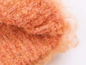 Gros plan sur un tricot en mohair orange moelleux montrant une texture douce en peluche