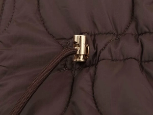 Gros plan détaillé de la veste matelassée marron foncé avec cordon à arrêt doré