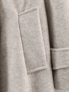 Close-up of light grey wool jacket pocket showing high-density fabric and neat stitching