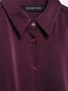 Close-up detail of burgundy satin shirt collar featuring buttons and brand label