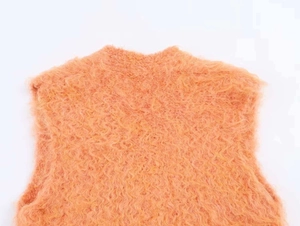 Détail du gilet en maille duveteuse orange montrant la texture mohair et le col en V