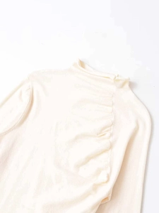 Detail view of cream long sleeve top with elegant ruching and refined knit texture