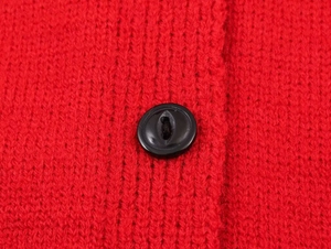 Close-up of red knit cardigan with ribbed texture and a polished black button detail