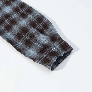 Close-up of long sleeve cuff with classic blue brown plaid pattern and clear button