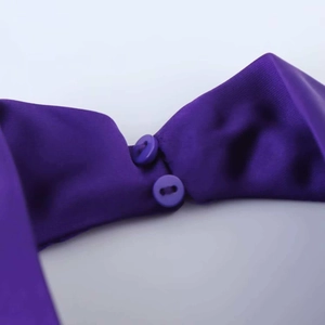 Macro detail of silk-like purple satin fabric with two matching functional buttons