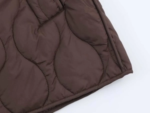 Détail du tissu matelassé marron foncé avec coutures ondulées d'une veste d'hiver