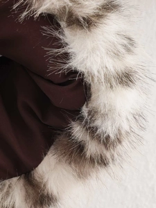 Détail du col en fausse fourrure pelucheuse et du tissu épais marron du manteau léopard