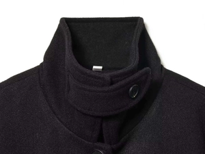 Close-up of black wool blend coat showing high collar structure and stitching detail