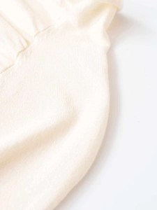 Detailed macro view of soft cream knit fabric texture and fine stitching on the sweater